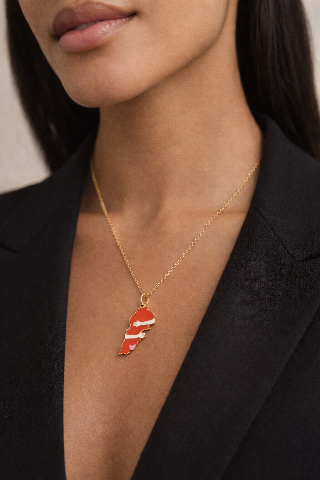 Necklace with a red and white striped pendant worn by a person in a black blazer.